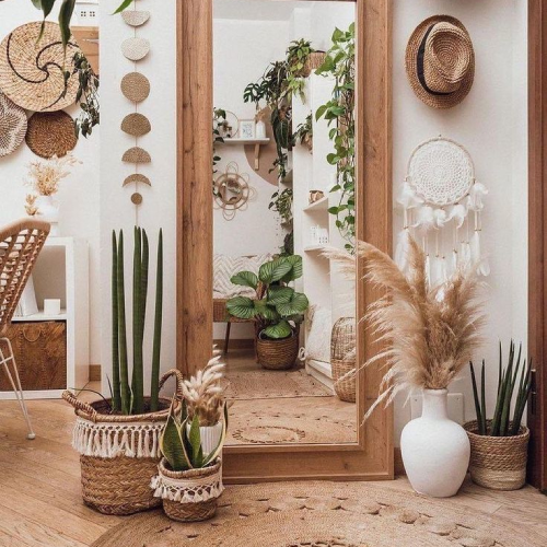 Boho entryway with a large wood-framed mirror, woven wall decor, and indoor plants